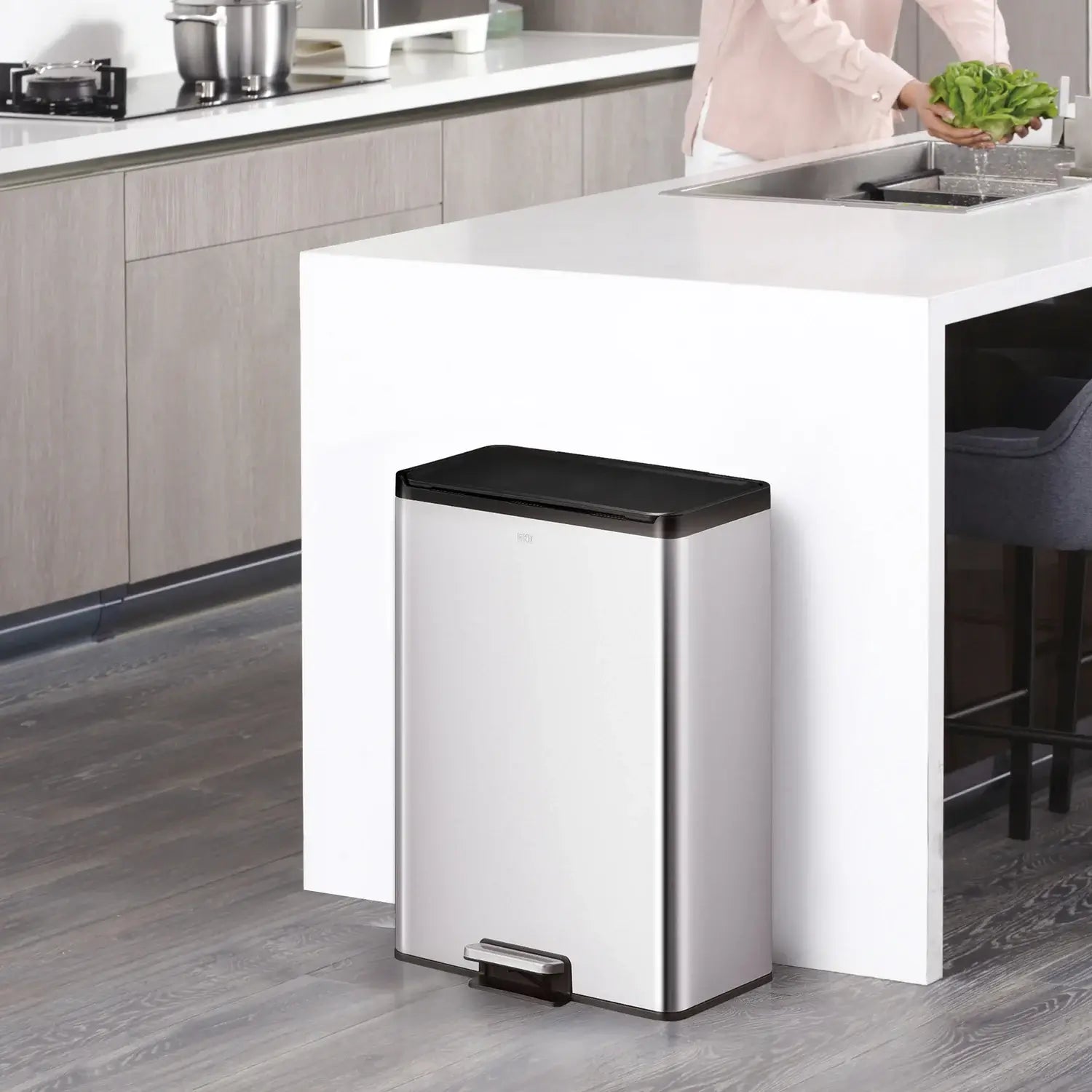 Stainless steel waste bin with black lid in a kitchen setting